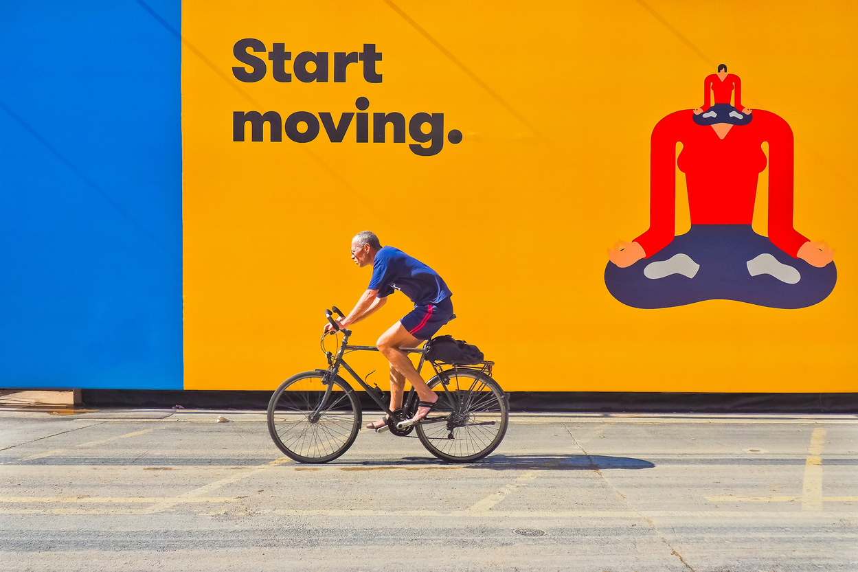 Cyclist in Front of Yellow Billboard